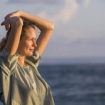 oung happy beautiful and glamorous blond woman posing as at the beach wearing stylish dress smiling cheerful feeling fresh and free in beauty fashion concept